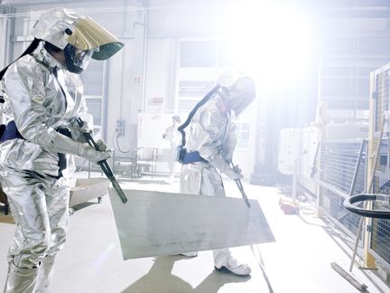 Zwei Werkstoffforscher tragen ein frisch gewalztes Magnesiumblech.